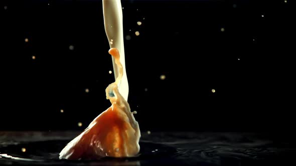 Stream of Milk with Splashes Falls Into Black Coffee