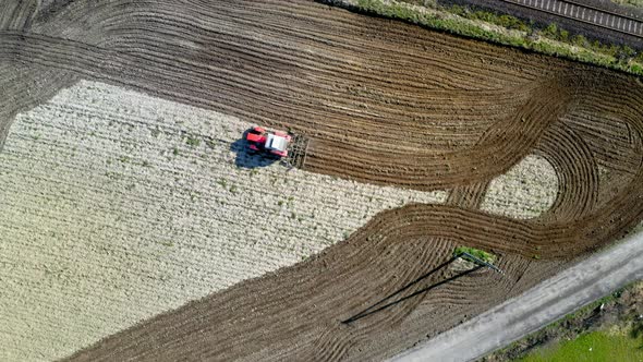 Red tractor plowing a field in spring, aerial view, Poland