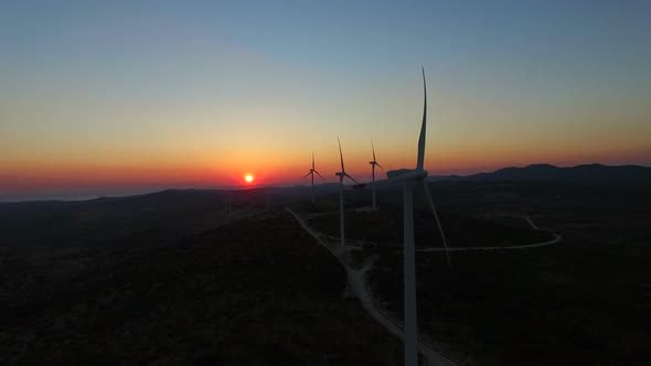 Aerial view of windmills with slowly rotating blades at sunset
