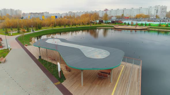 Arbor with Benches on Wooden Pier Over Pond in Garden