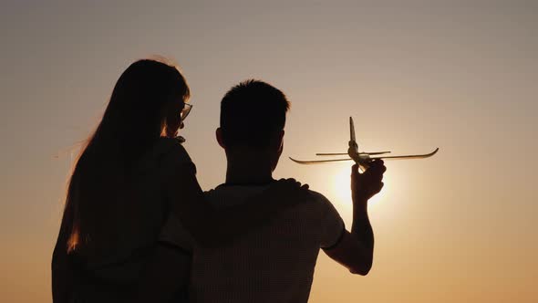 Silhouette of a Man Playing with a Girl with a Toy Plane