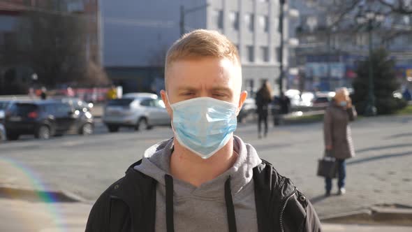 Guy Wearing Protective Mask From Virus Outdoor in the People Crowdy. Portrait of Young Man with