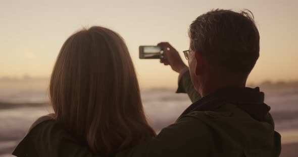 Active senior couple taking picture on beach