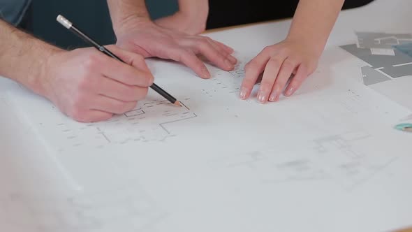 Close Up Hands of Two Workers Discussing Building Drawings in Office. Closeup Shooting of Arms