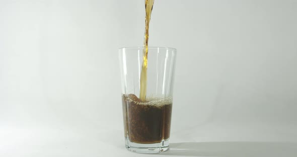 Cola beverage being poured into glass with a clear background