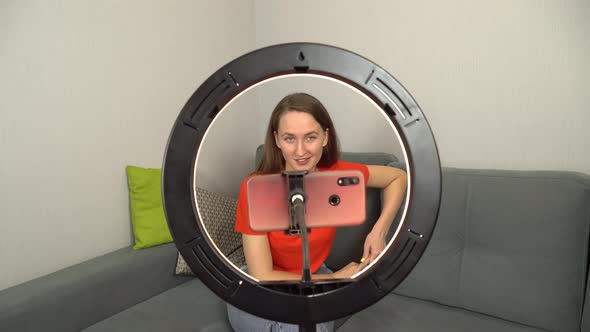 a female blogger talks to her followers on a mobile phone camera at home.