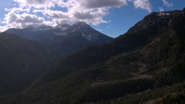 Aerial view moving over mountain layers towards a snow capped peak