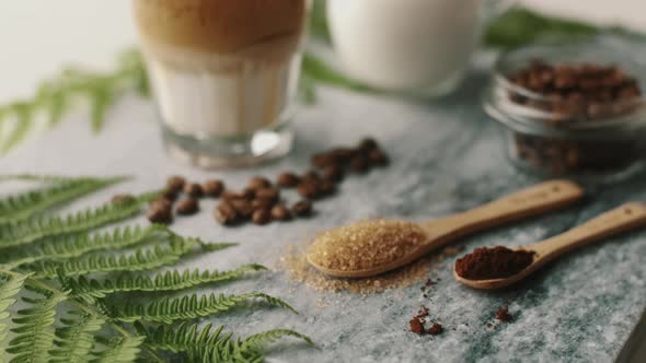 Close up Dalgona coffee with almond milk and brown sugar, beans on marble board