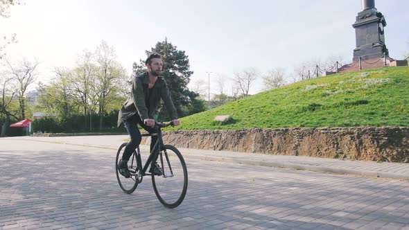 Tracking Shot of Hipster Man Riding Fixed Gear Bicycle in Park Slow Motion