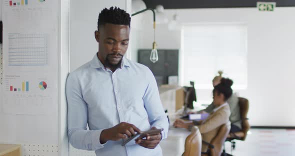 Portrait of happy african american businessman with tablet in creative office