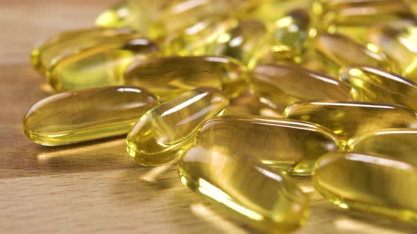 Yellow medical capsules with fish salmon oil on a wooden surface