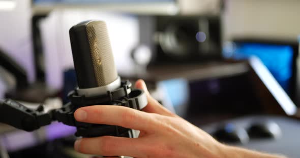 A hand setting up a pop filter for a condenser microphone in a music studio for recording a vocalist