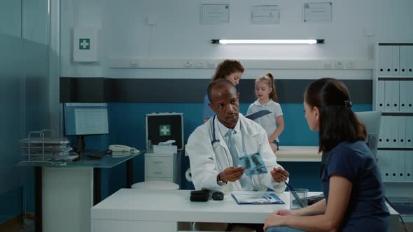 Professional Medic Explaining x Ray Results to Mother at Appointment