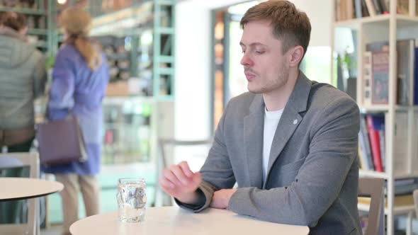 Young Man Drinking Water in Cafe