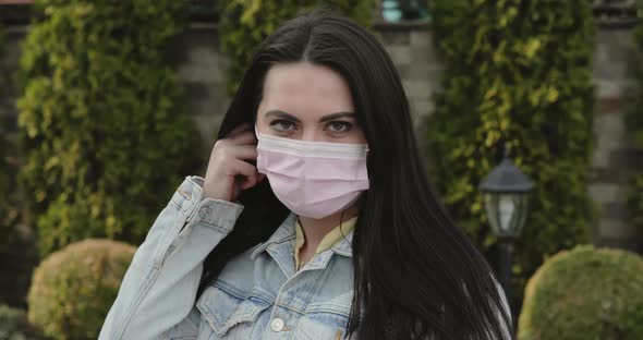 Cured Girl in Garden Undresses Medical Mask Corrects Hair and Smiles at Camera