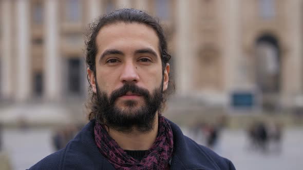 Confident Attractive latin young man looking at camera- city in background