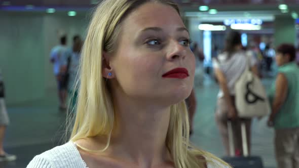 A Young Beautiful Woman Looks Around in a Train Station Building - Face Closeup