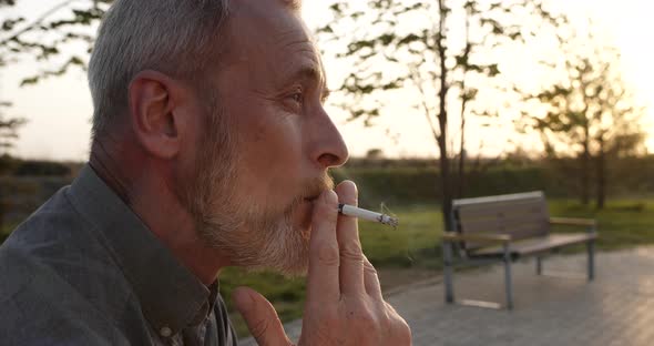 The Old Man Smokes a Cigarette Sadly