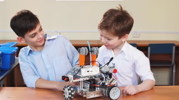 Two Brothers Kids Playing with Robot Toy at School Robotics Class, Indoor.