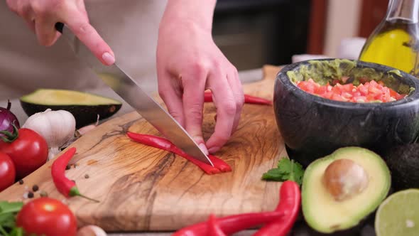 Making Guacamole Sauce  Woman Slicing Chili Pepper on a Wooden Cutting Board