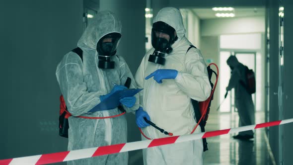 Inspectors in Hazmat Suits Talking and Taking Notes. Coronavirus, Covid-19 Concept.