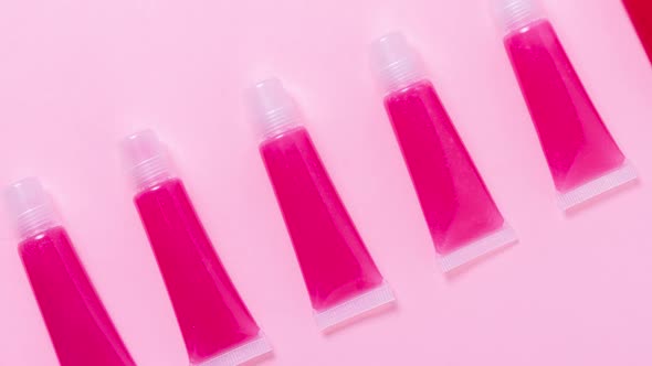 Lot of homemade lip glosses on pink background