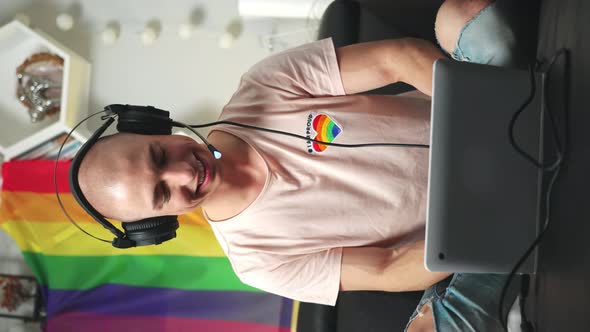 Bald Caucasian Gay Gamer Playing Computer Games on His Laptop While Sitting on a Black Sofa