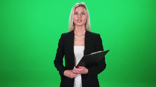 Woman Reporter in Suit Looks Into the Camera and Speaks in Lavalier Microphone Holding a Folder of