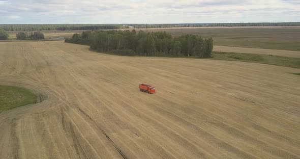 Bird Eye View Truck Drives Along Harvested Field To Thresher