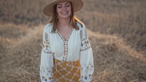 Happy Playful Woman Falls Into Haystack in Wheat Field at Sunset