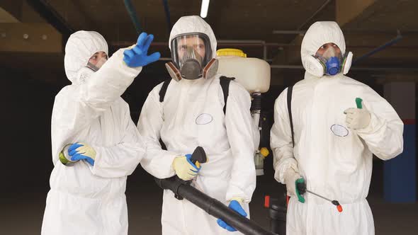 Portrait of Three Sanitation Workers in Protective Gear Suit Medical Mask Gloves