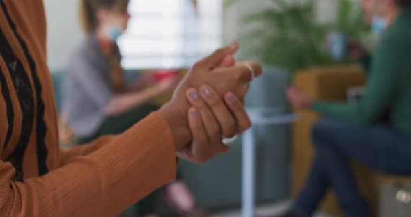 Mid section of woman sanitizing her hands at office