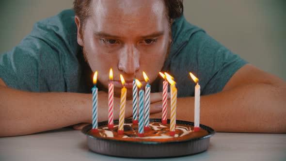 Sad Man Is Blowing Out the Candles on the Birthday Cake