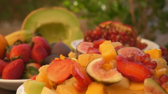 Super Closeup of the Pomegranate Seeds Falling on the Salad Made of Fruits