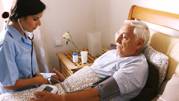 Nurse checking blood pressure of senior man in bedroom