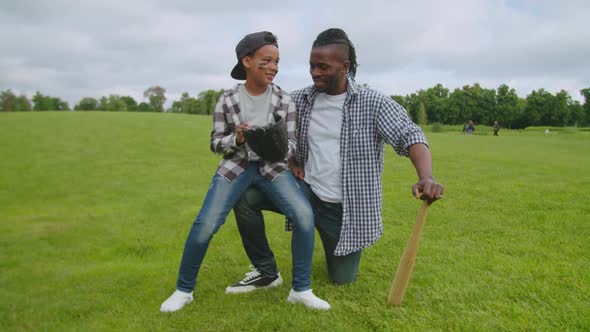 Active Black Father and Son Enjoying Baseball Game in Park