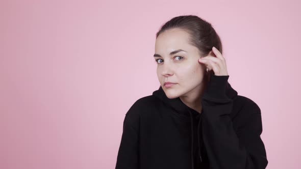 Woman Looking at Camera Like Mirror Fixing Her Hair Isolated on Pink Background