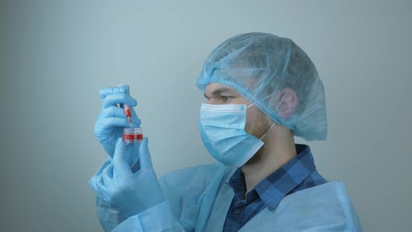 Coronavirus covid-19. Male doctor holding blood sample and syringe for injection. Pandemic concept
