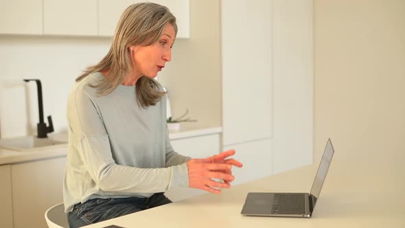 Goodlooking Senior Mature Woman is Using Laptop for Video Connection Making a Call