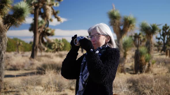 An adult woman photographer taking pictures with her old fashioned film camera in a desert wildlife