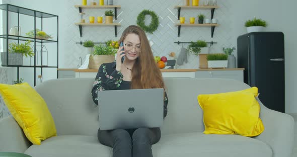 Caucasian Attractive Young Woman in Glasses Working on the Laptop Computer on the Couch in the
