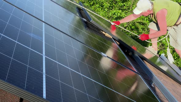 Man Installs and Fastens PV Solar Panels on Roof of His Own House