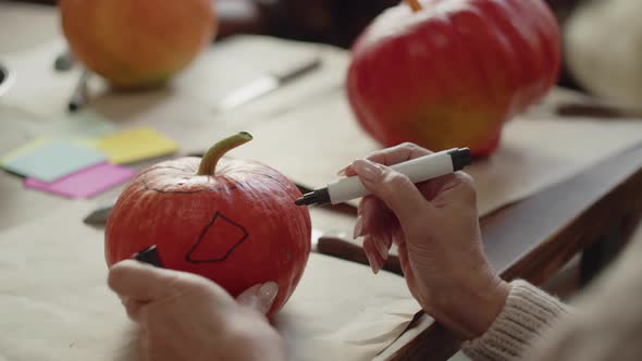 The Woman Draws on the Pumpkin with a Marker