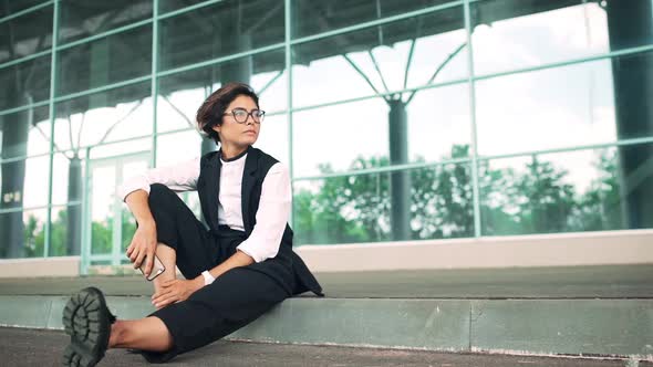 Young Beautiful Businesswoman Sitting on Street Business Centre Background