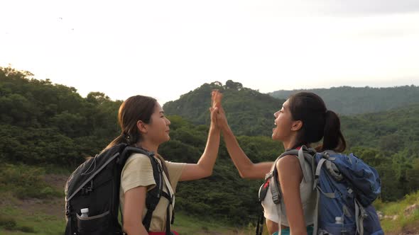 Two young female trekkers proudly arrived at their destination in the midst of beautiful nature.