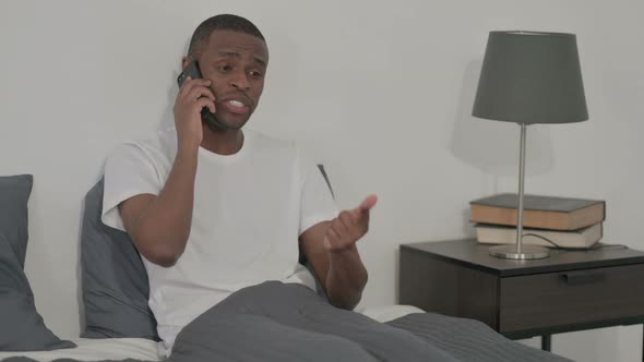 African Man Talking on Call on Smartphone in Bed