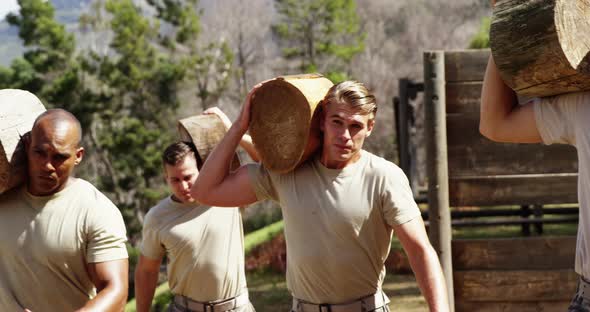 Military troops carrying heavy wooden logs during obstacle course