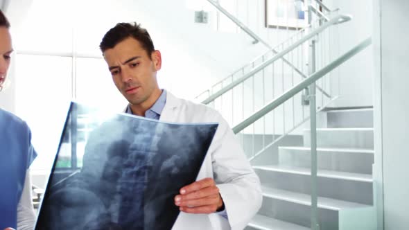 Doctor and nurse discussing over x-ray report in corridor