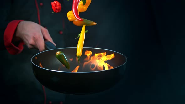 Super Slow Motion Shot of Chef Holding Frying Pan and Falling Chilli Peppers Into Fire at 1000Fps