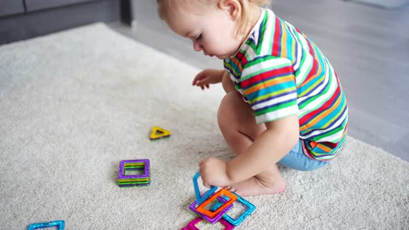 Little Girl Playing Colorful Magnet Plastic Blocks Kit at Home